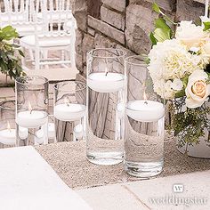 white flowers and candles sit in vases on a table