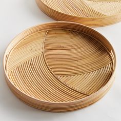 two round bamboo trays sitting on top of a white table next to each other