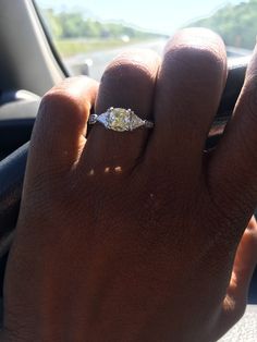 a person's hand with a diamond ring on their finger in a car steering wheel