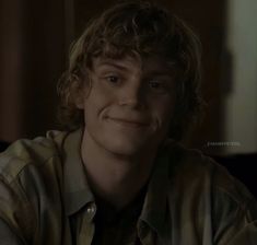 a young man with curly hair smiling at the camera