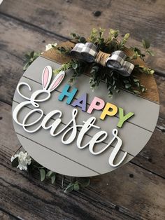 a sign that says happy easter on top of a wooden table with flowers and greenery