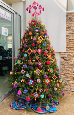 a brightly colored christmas tree in front of a building