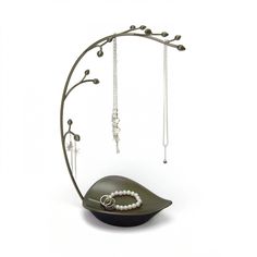 a necklace holder with pearls and chains hanging from it's sides on a white background