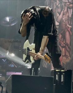 a man holding a guitar while standing on top of a stage