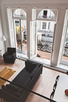 a living room filled with black furniture and lots of windows covered in white trimming