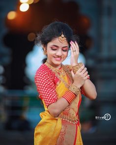 a woman in a yellow and red sari holding her hands together