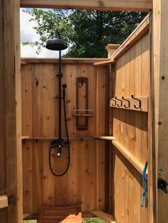 a wooden shower in the middle of a yard with an open door and rain head