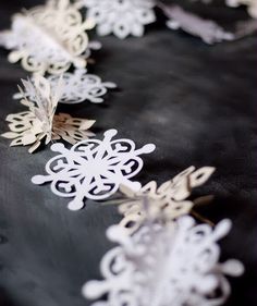 paper snowflakes are lined up on a black tablecloth with gold and white decorations