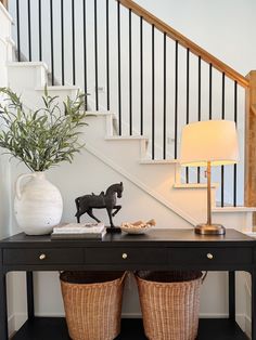 a black table with two baskets underneath it and a lamp next to it on the side