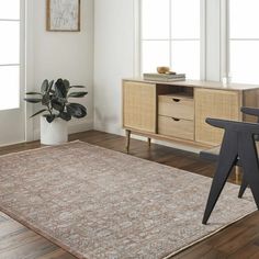 a living room area with a rug, sideboard and plant in the corner on the floor