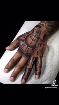 a man's hand with a clock tattoo on it