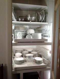 an open cabinet filled with dishes and glasses