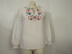 "Vintage 1960s or 70s peasant shirt bohemian ethnic blouse. Made of white cotton or poly/cotton. Has colorful embroidered decoration. String tie at the neck. No label. Fits like a size large. Actual measurements are: 38\" at the bust 39\" at the waist 18\" shoulder seam to shoulder seam 20\" shoulder seam to end of sleeve 23\" overall length In very good condition with a small light rust mark on the shoulder(photo)." Shoulder Photo, Vintage Peasant Blouse, Embroidered Decoration, Bohemian Shirt, Peasant Shirt, Hippie Shirt, Peasant Blouse, Small Light, Embroidered Shirt