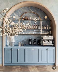 a blue bar with lots of bottles on the shelves and flowers in a vase next to it