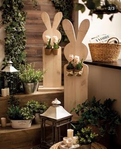 two wooden rabbits sitting on top of some steps next to potted plants and candles