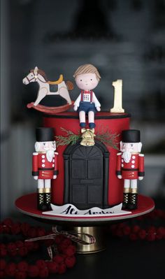 a red cake decorated with nutcrackers and figures on it's stand