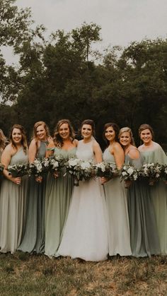 a group of women standing next to each other on top of a grass covered field