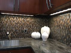 two white vases sitting on top of a kitchen counter next to a silver sink