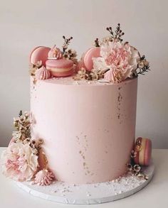 a pink cake decorated with flowers and macaroons