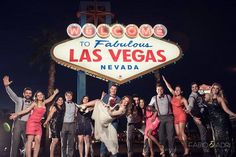 a group of people posing in front of the welcome to fabulous las vegas sign at night