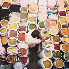 a woman standing in front of bags filled with different types of spices and seasonings