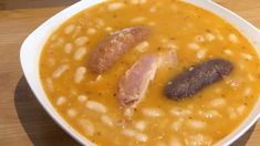 a bowl of soup with beans and sausage on the side, ready to be eaten