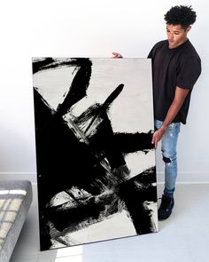 a man holding up a large black and white painting