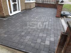 a brick patio in front of a house with a car parked on the driveway next to it