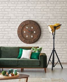 a green couch in front of a brick wall with a large clock on the wall