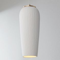 a white lamp hanging from a ceiling in a room with a light on the side