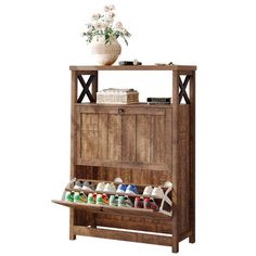 a wooden shoe rack with shoes on top and flowers in the bottom shelf next to it