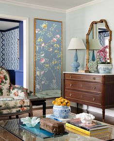 a living room filled with furniture and a painting on the wall next to a coffee table