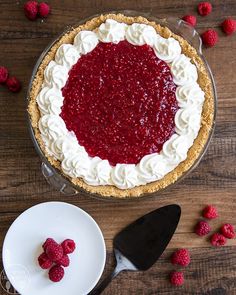 a raspberry pie with whipped cream and fresh raspberries on the side