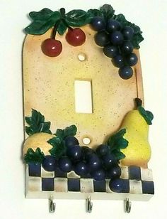 a decorative light switch plate with grapes and pears on it