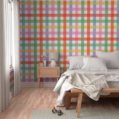 a bedroom with colorful plaid wallpaper and wooden flooring