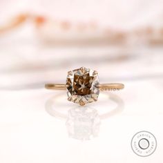 a brown diamond ring sitting on top of a white surface