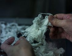 someone is peeling something white with their hands on the edge of an object that appears to have been made out of yarn