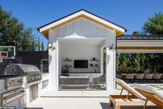 an outdoor kitchen and living area with bbq in the back ground, covered by white roofing