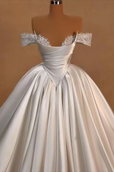 a white wedding dress on display in front of a mannequin headdress