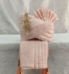 two pink bags with tassels on them sitting on a white cloth covered bench