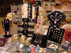 there are many necklaces on display at the table with other items in front of them