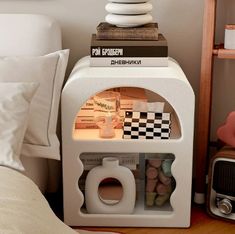 a white toilet paper dispenser sitting on top of a wooden shelf next to a bed