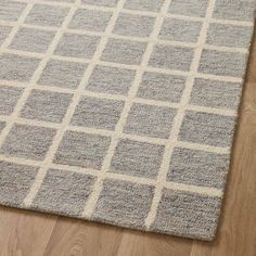 a gray and white rug with squares on the floor in front of a wooden floor