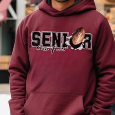 Introducing the ultimate Senior Class of 2024 custom name and number football hoodie, where style meets spirit!  🏈🎓 Picture your graduate stepping onto the field, their name and number proudly displayed on this exceptional hoodie. It's not just an outfit; it's a living testament to their dedication and the unforgettable journey they've embarked on. 💫 This hoodie is more than apparel; it's a symbol of your Senior's athletic prowess and an embodiment of their commitment to excellence. It's a tangible reminder of the victories they've achieved and the victories yet to come. 🌠 As a parent, you've watched your child's passion for the game grow from the very first kick to this triumphant moment. This hoodie encapsulates their achievements and the unwavering support that has been the driving Pre-shrunk School Spirit Hoodie For Sports Season, Collegiate Style Hoodie For Game Day, Sports Season, College Team Spirit Hoodie With Letter Print, College Hoodie With School Spirit Letter Print, College Hoodie With Letter Print And School Spirit Style, Football Season Hoodie With Letter Print For Sports Events, Sports Fan Hoodie With Team Name, Sports Fan Hoodie With Team Name For Streetwear, Sports Fan Hoodie For Sports Season