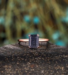 a gold ring with a blue diamond on it sitting on top of a large rock