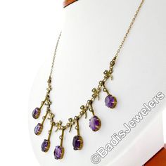 "You are looking at a rare antique collier necklace crafted in solid 14k yellow gold during the Victorian era. The center part of this beautiful necklace features elegant fringe designs alternating with clover leaf accents throughout. Each of these 7 dangle parts is set at its bottom with an old oval cut amethyst stone that shows amazing, rich purple color, and all 7 of them total approximately 14 carats in weight. The top of these fine gemstones, as well as the pretty leaf designs, are adorned Antique Oval Gemstone Necklace, Victorian Purple Necklace For Anniversary, Antique 14k Stamped Necklaces For Formal Occasions, Antique Oval Purple Necklaces, Antique Amethyst Jewelry Stamped 14k, Antique Oval Purple Jewelry, Antique Round Purple Necklace, Antique Purple Oval Necklaces, Victorian Style Gemstone Necklaces For Anniversary