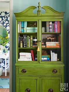 a green china cabinet with books on it