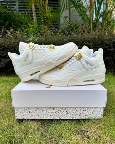 Embrace timeless elegance with these Air Jordan 4 Retro "Sail" -inspired sneakers. The pristine sail white upper exudes sophistication, while metallic gold accents on the eyelets and Jumpman logo add a touch of luxury. Crafted with meticulous attention to detail, these shoes offer a premium look and feel, perfect for elevating your everyday style. Luxury High-top Sneakers With Perforations For Streetwear, Luxury Low-top Cream Sneakers, Luxury Cream Low-top Sneakers, Luxury High-top Sneakers With Perforated Toe Box, Luxury Cream Sneakers For Streetwear, Gold Leather Sneakers For Streetwear, Modern Gold High-top Sneakers, Gold Leather High-top Sneakers With Boost Midsole, Gold Modern Sneakers For Streetwear