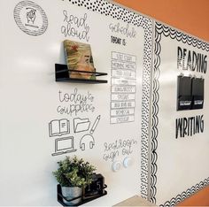 a white board with writing on it and some plants in the corner next to it