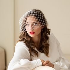 a woman wearing a veil and sitting on a couch with her hands folded over her face